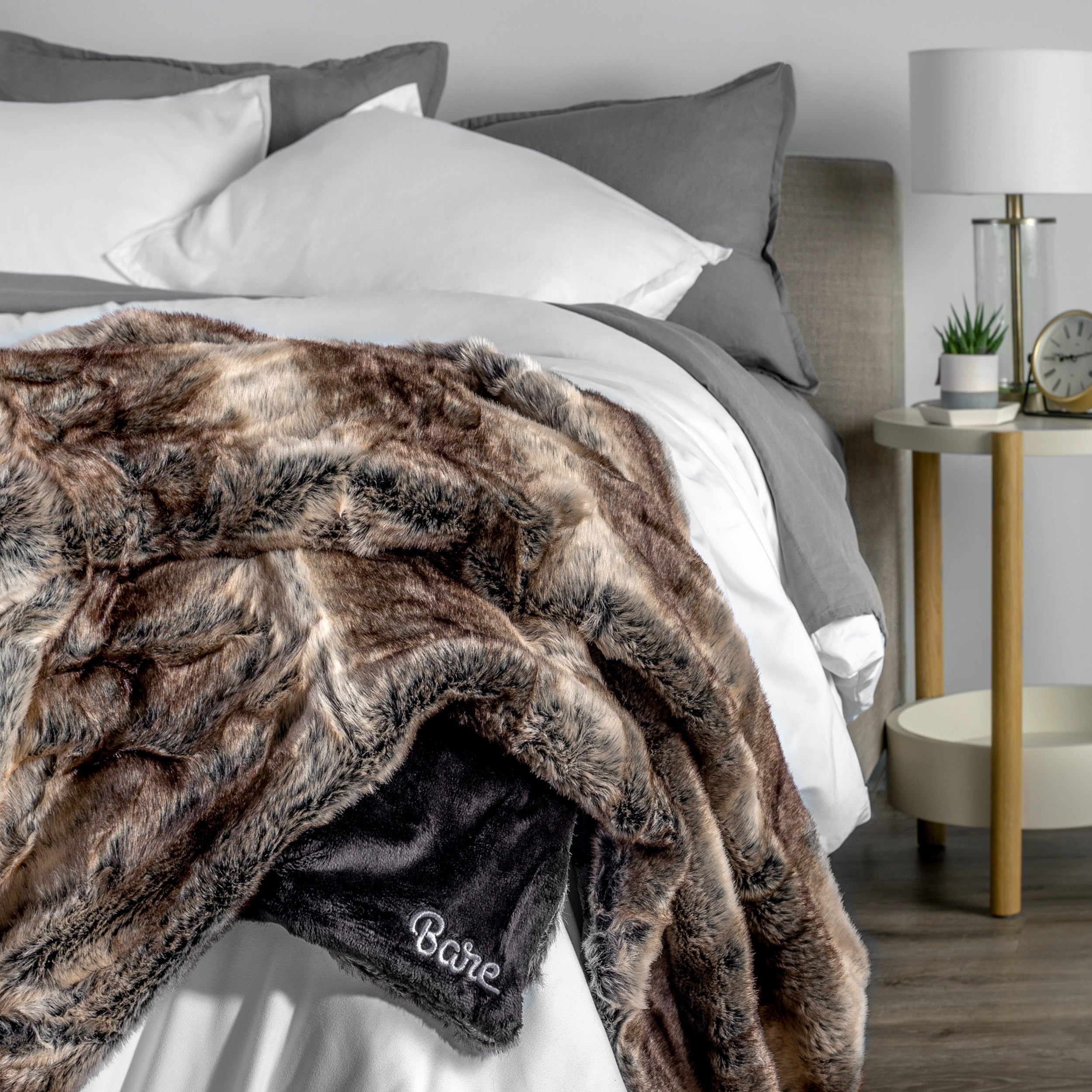 Blanket with 'Bare' branding on a bed in a bedroom setting