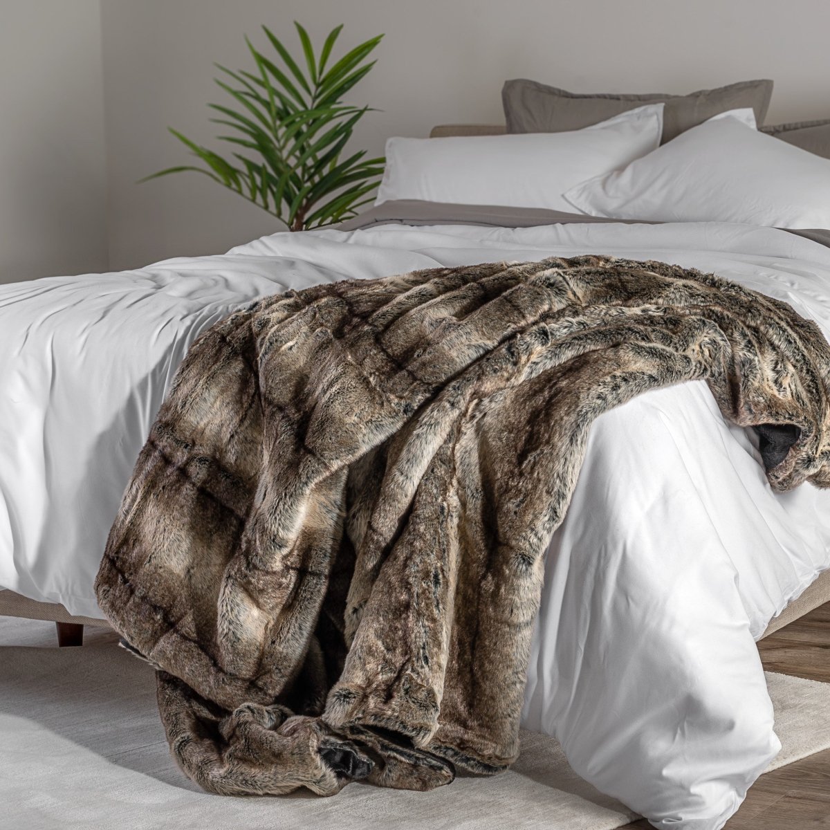 Blanket draped over a bed in a bedroom setting with a nightstand and lamp.