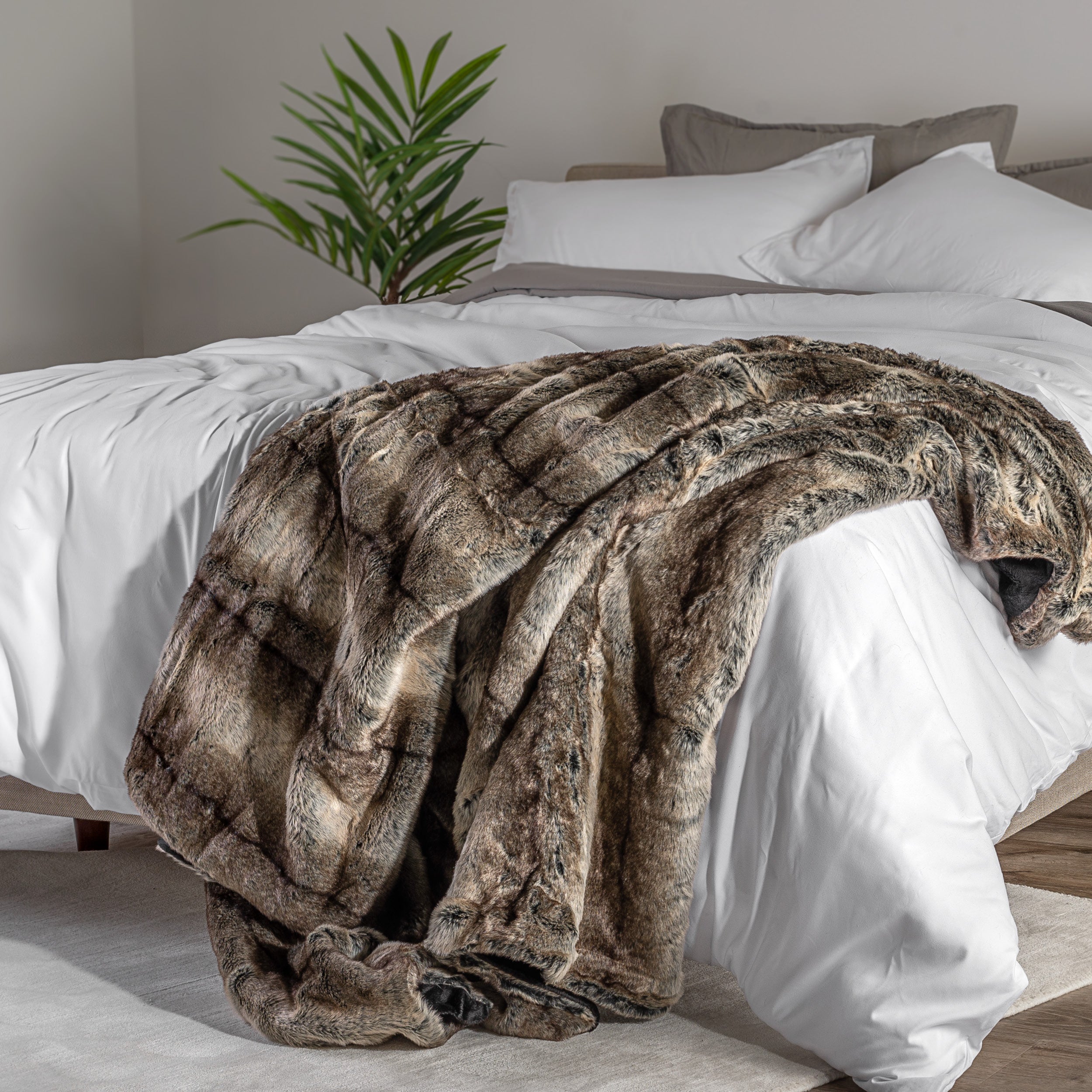 Blanket draped over a bed in a bedroom setting with a nightstand and lamp.