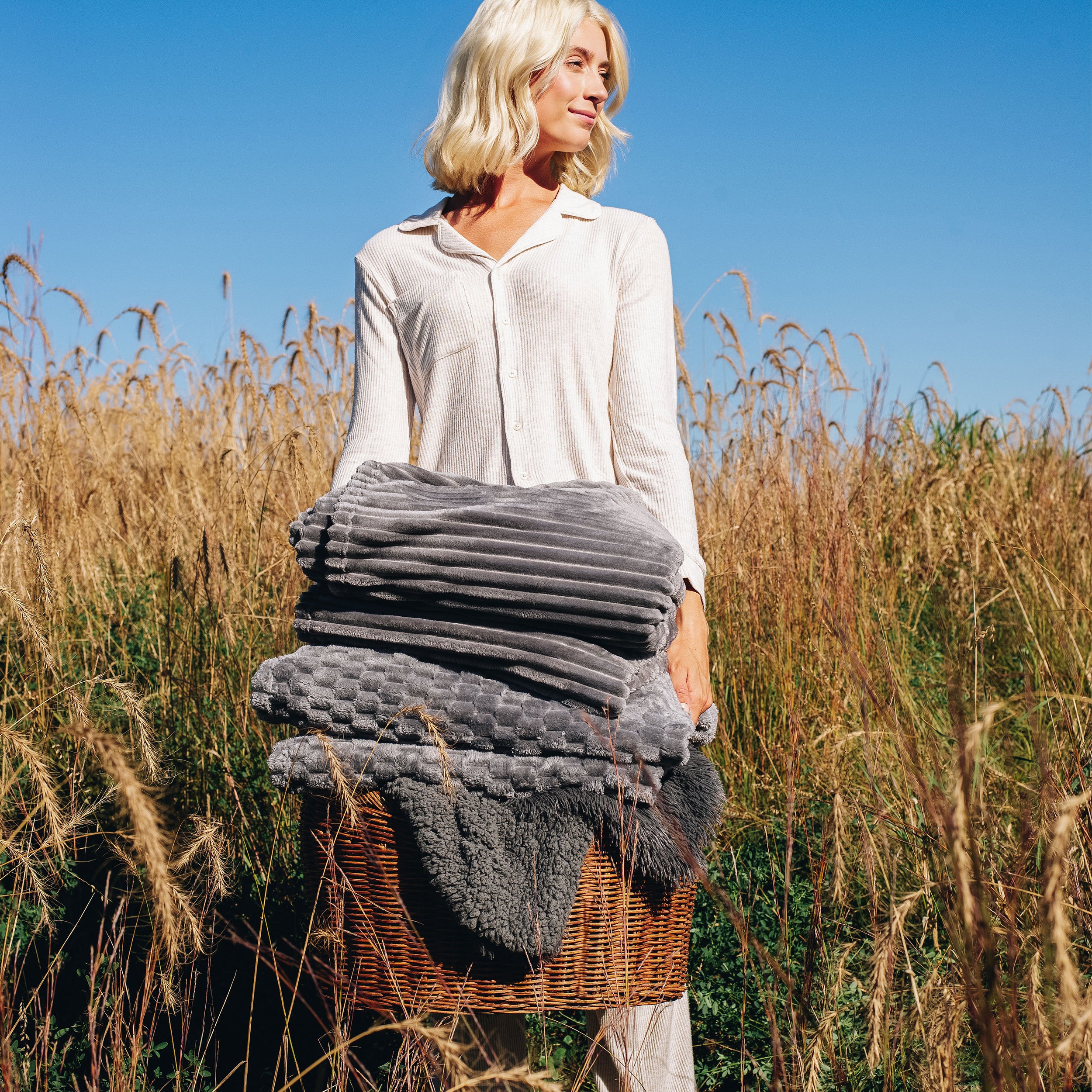 Woman in a field with a basket of blankets
