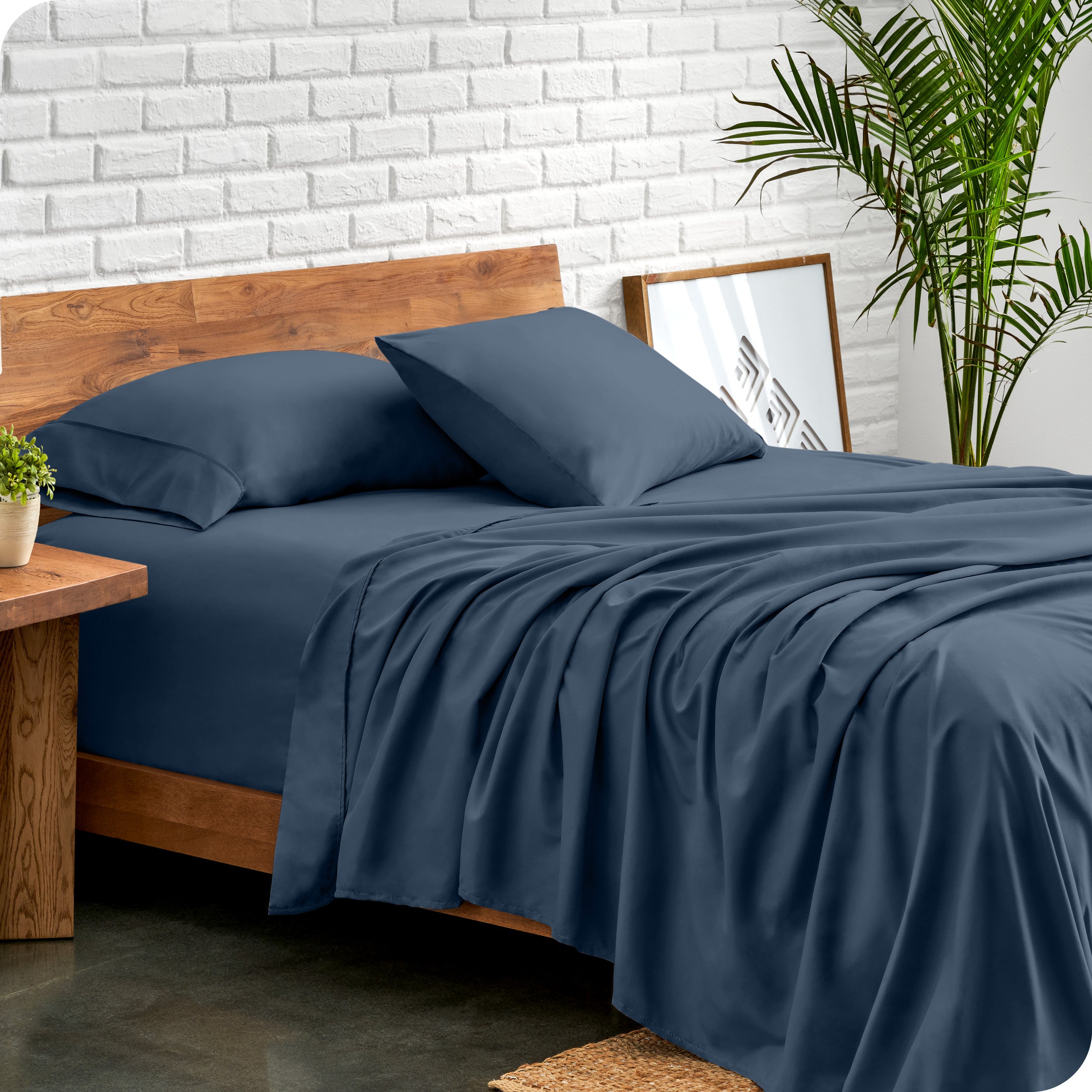 Bed with microfiber sheets against a white brick wall