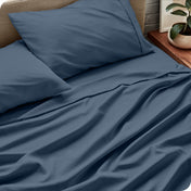 Sheet set on a bed with pillows and a plant in the background