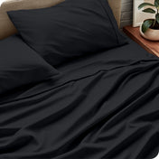 Sheet set on a bed with pillows and a plant in the background