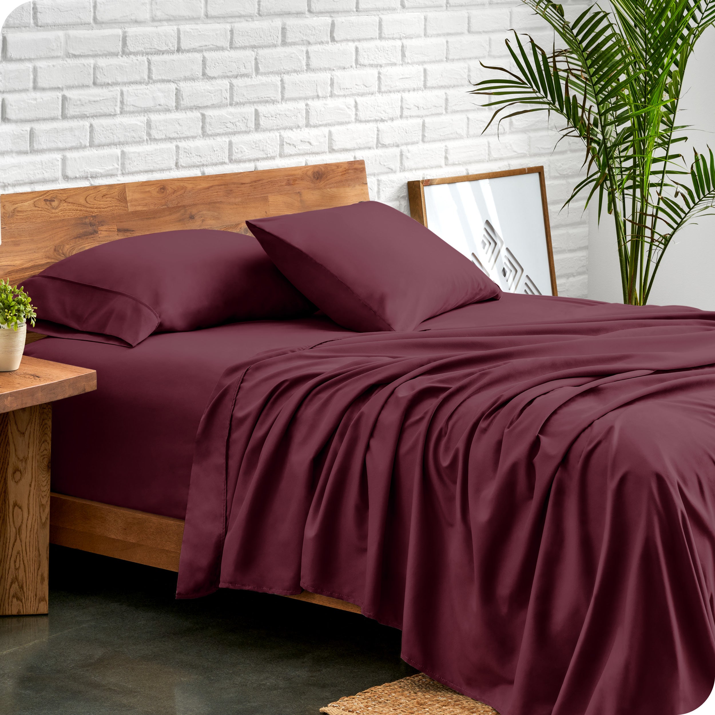 Bed with microfiber sheets against a white brick wall
