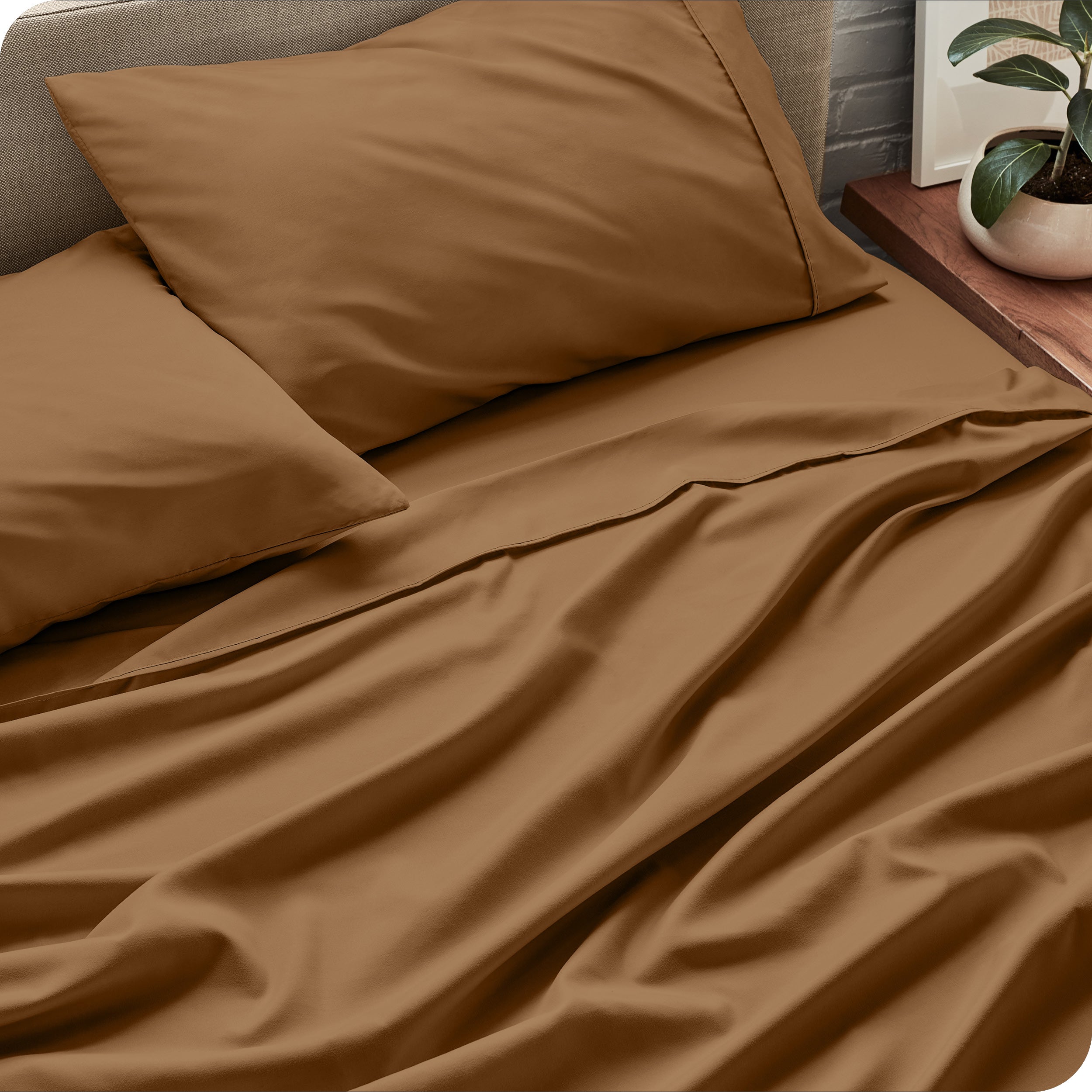 Sheet set on a bed with pillows and a plant in the background