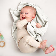 A baby lying on a receiving blanket. She has her thumb in her mouth.