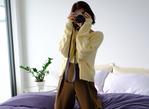 Woman standing on a balcony taking a photo with her phone, affiliate program graphic