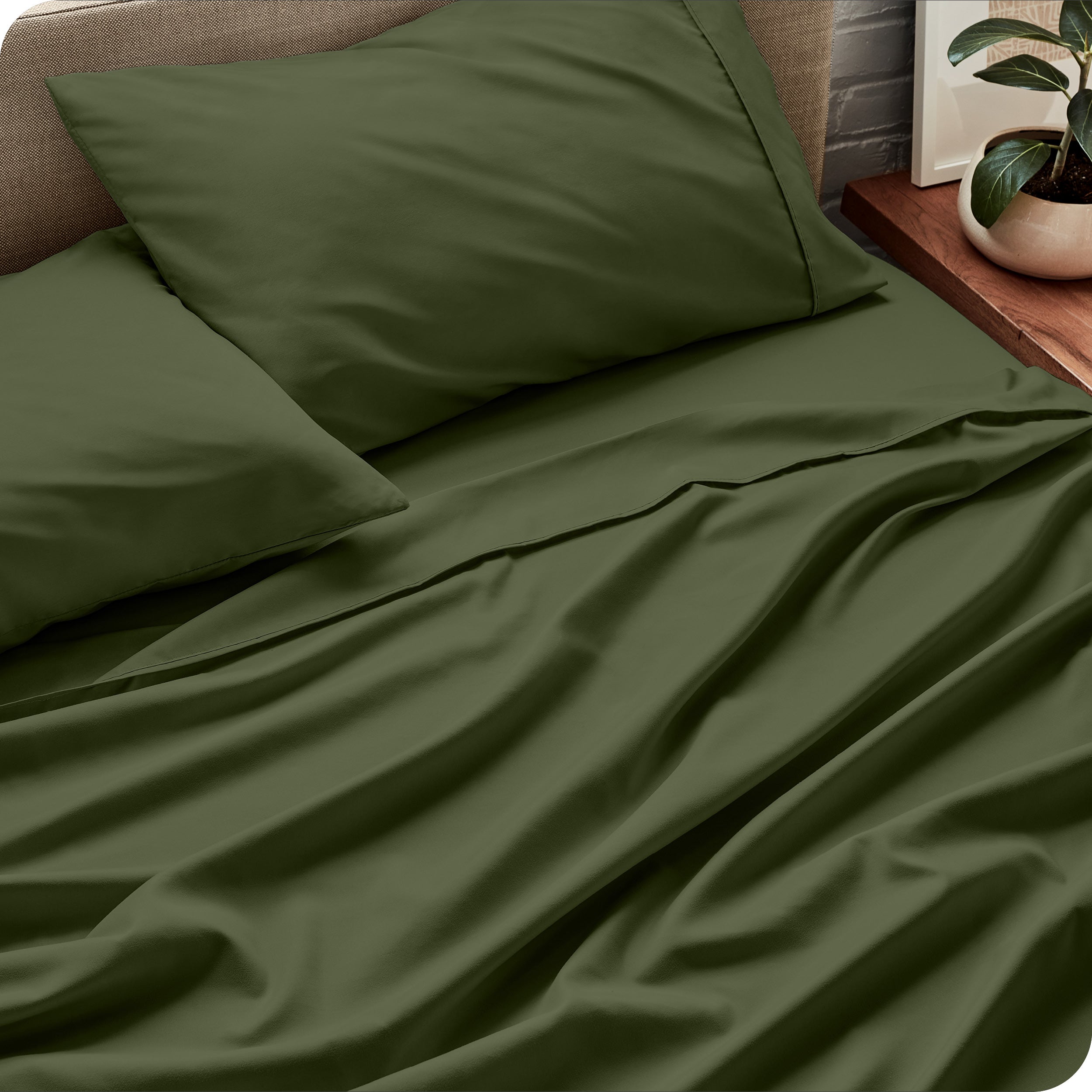Sheet set on a bed with pillows and a plant in the background