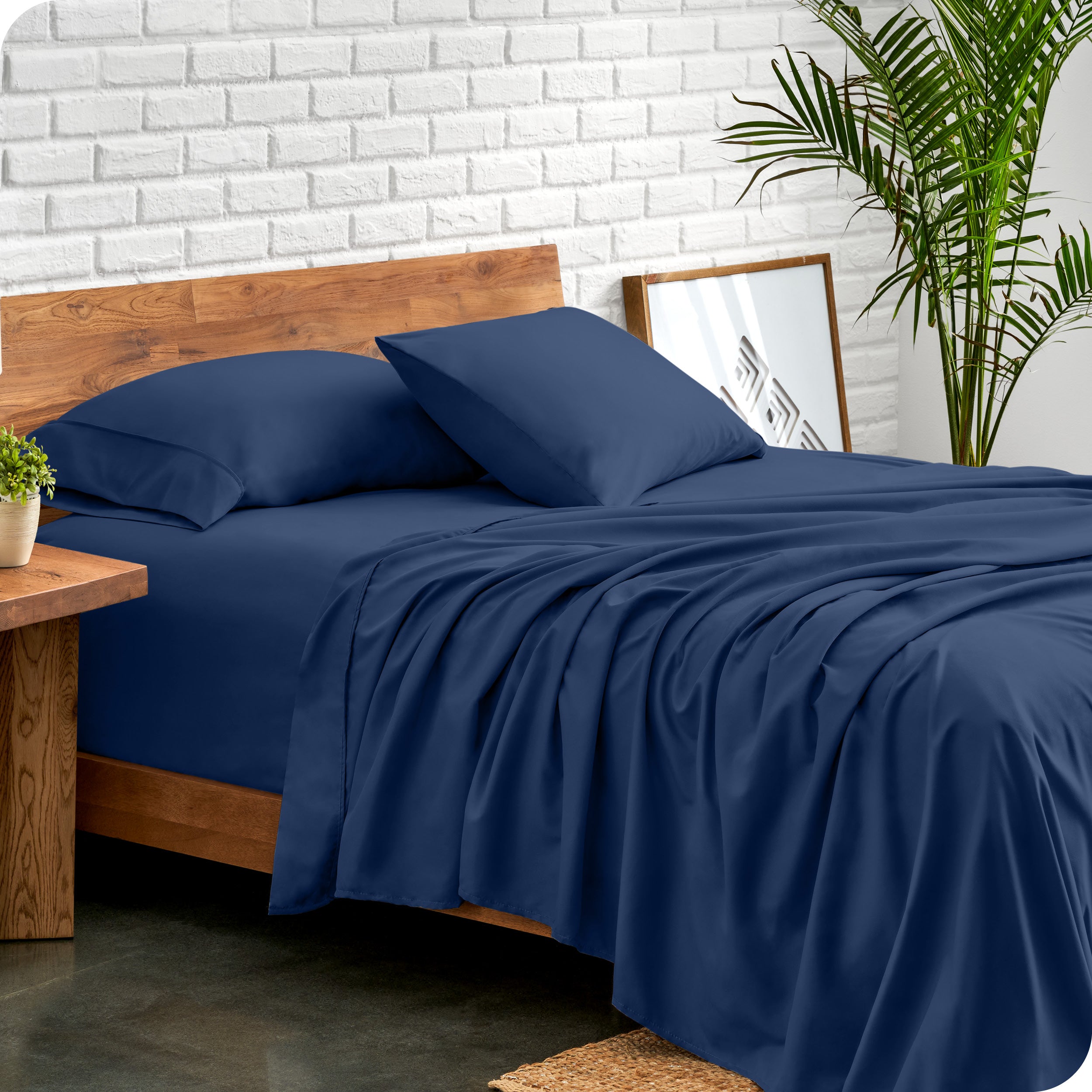 Bed with microfiber sheets against a white brick wall