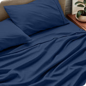Sheet set on a bed with pillows and a plant in the background