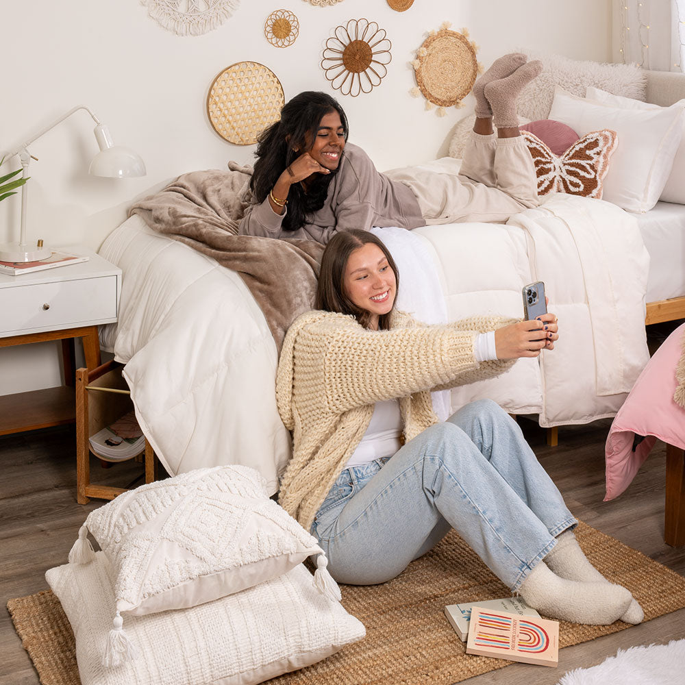 Two young ladies hanging out in a dorm room on beds
