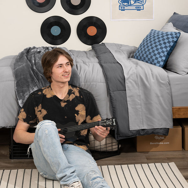 Young college student playing the ukulele  in his dorm room
