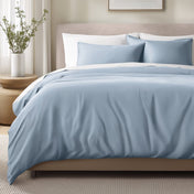 Bed with sateen bedding and pillows in a bedroom setting