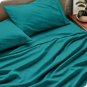 Sheet set on a bed with pillows and a plant in the background
