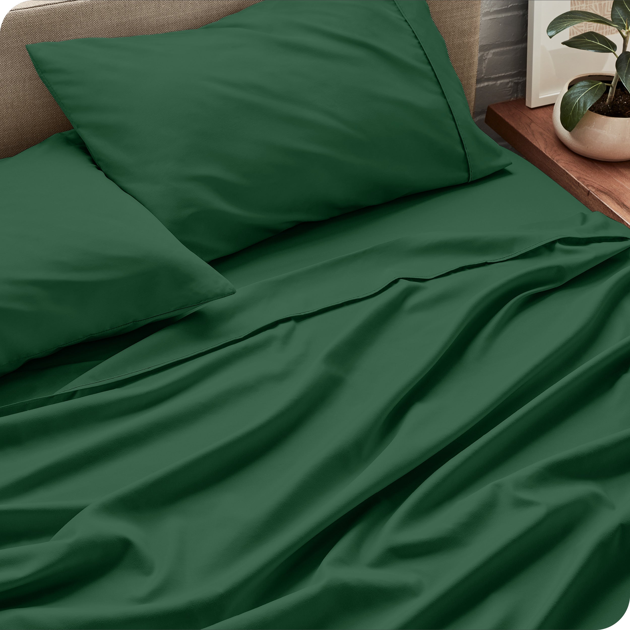 Sheet set on a bed with pillows and a plant in the background
