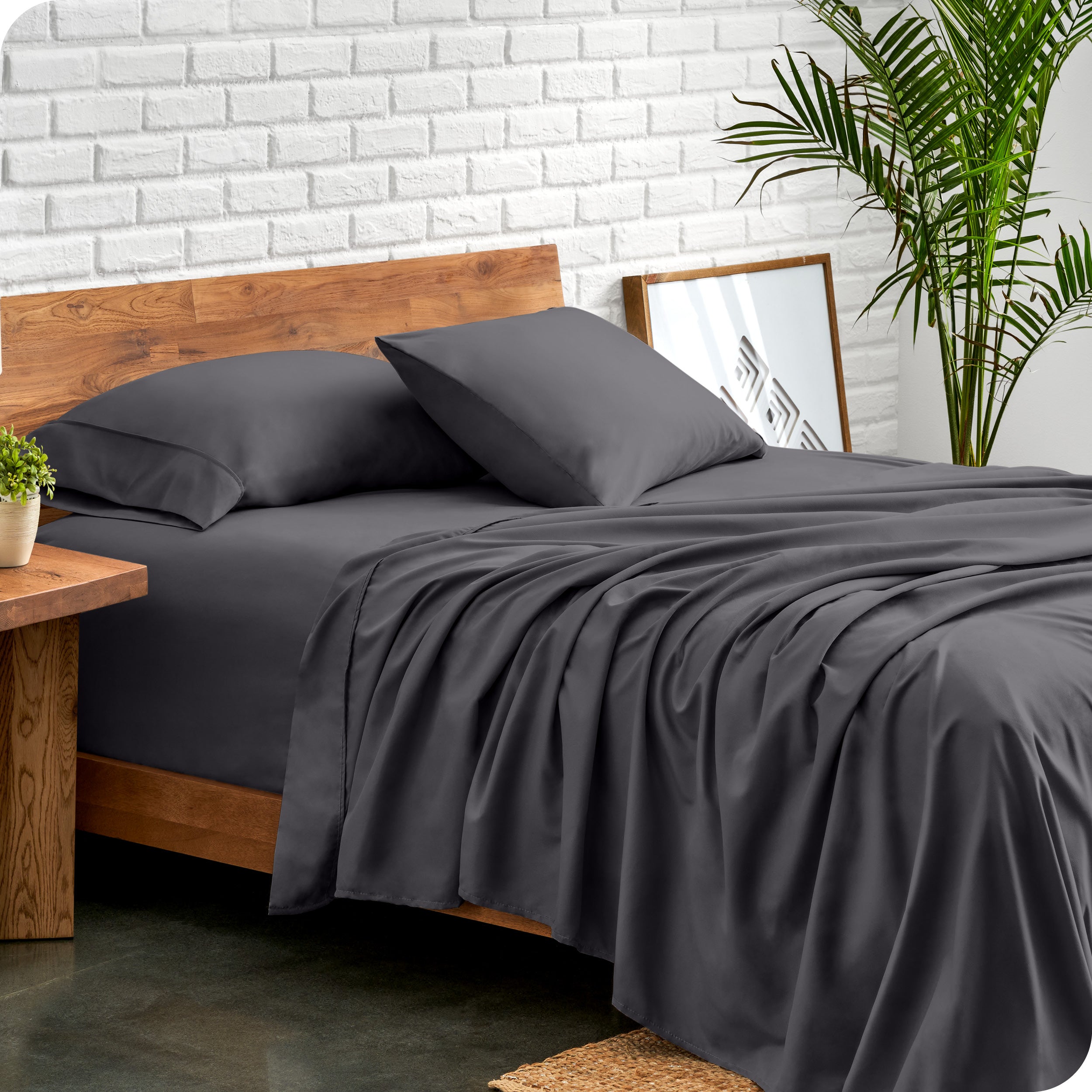 Bed with microfiber sheets against a white brick wall