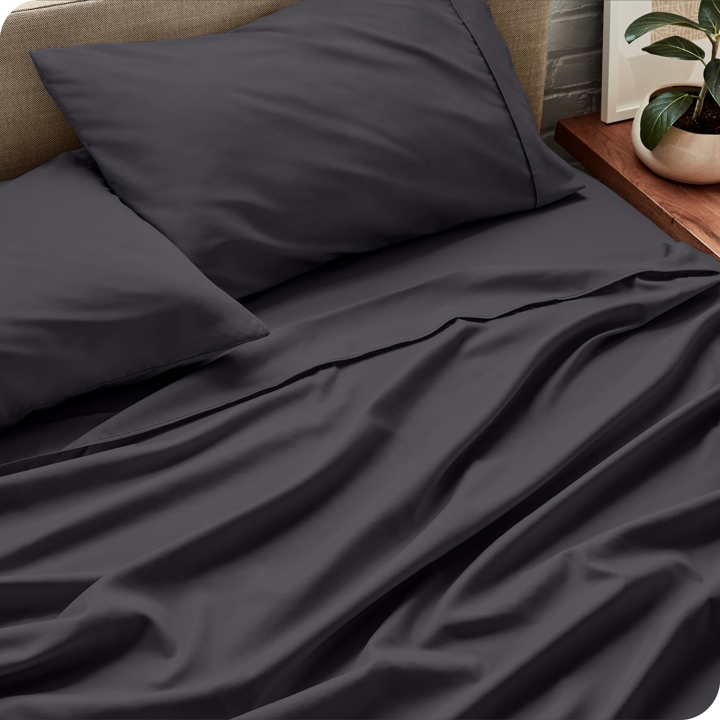 Sheet set on a bed with pillows and a plant in the background