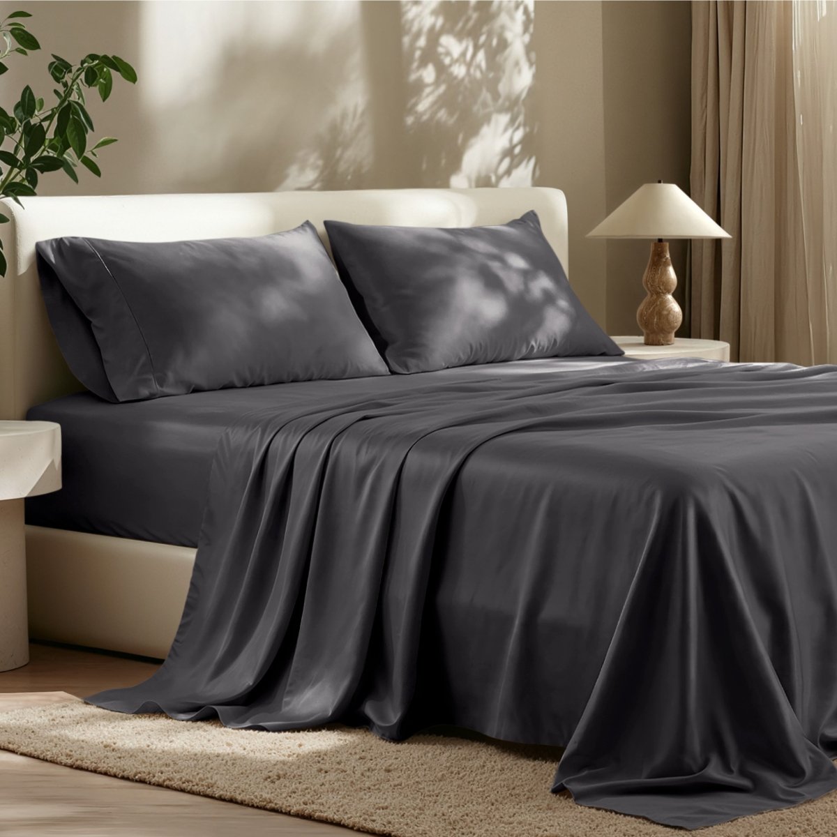 Sheet set on a bed in a bedroom with a lamp and plant.