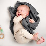 A baby lying on a receiving blanket. She has her thumb in her mouth.