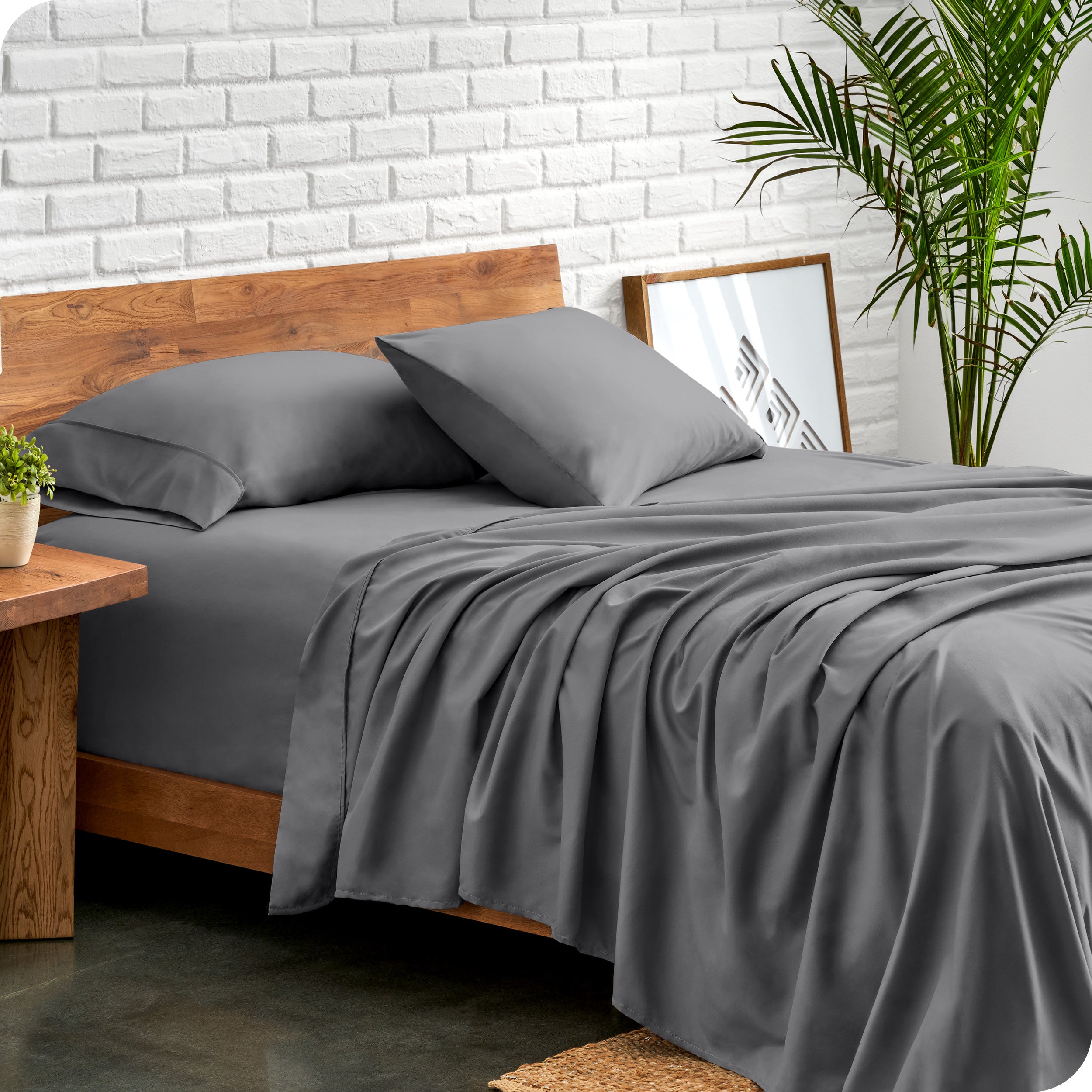 Bed with microfiber sheets against a white brick wall