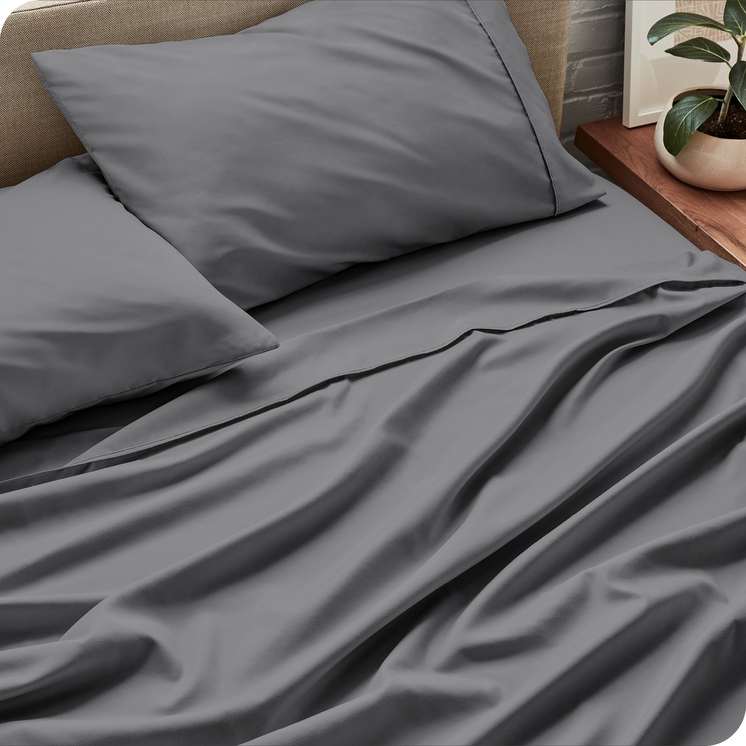 Sheet set on a bed with pillows and a plant in the background