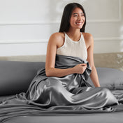 Woman sitting on a bed with a satin sheet over her