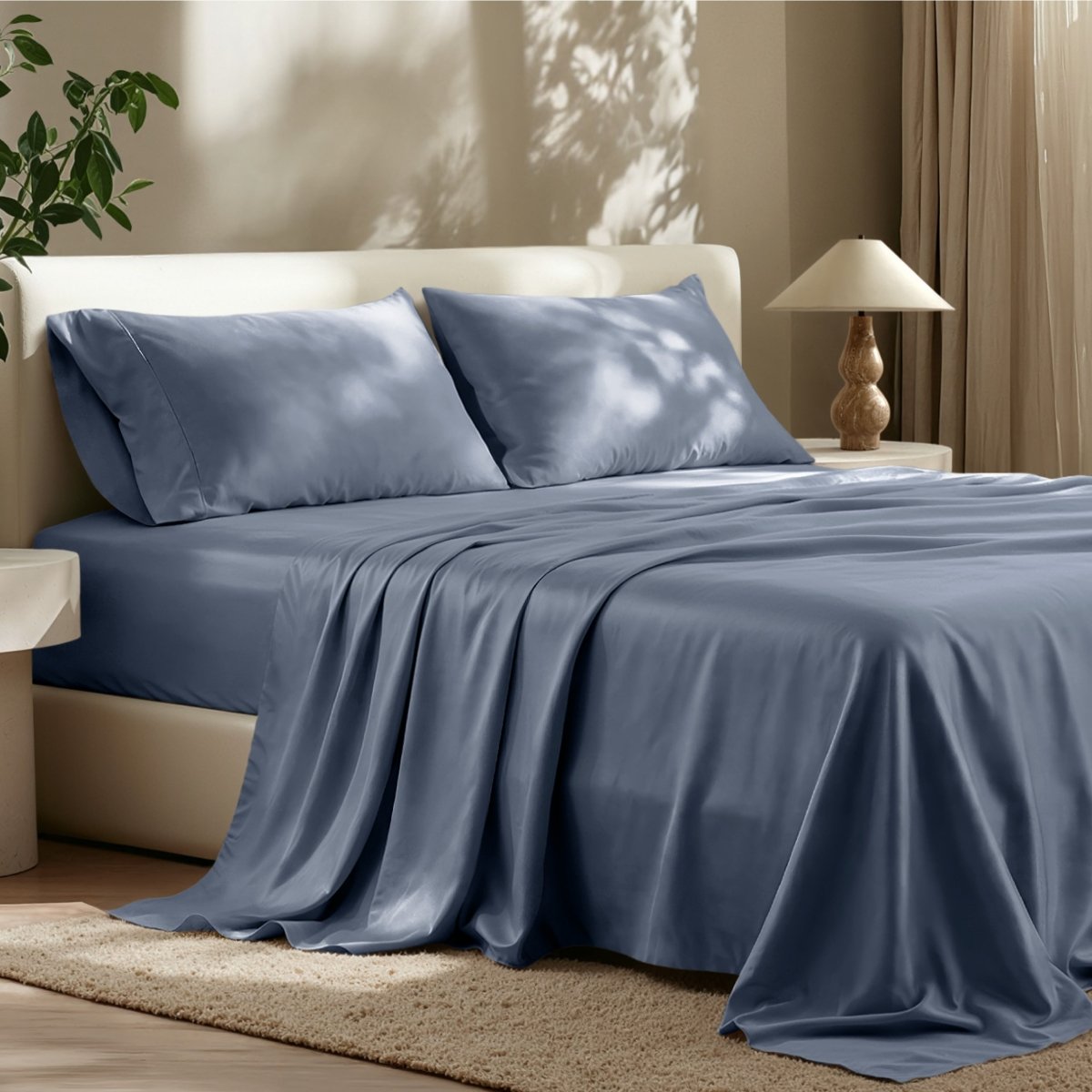 Sheet set on a bed in a bedroom with a lamp and plant.
