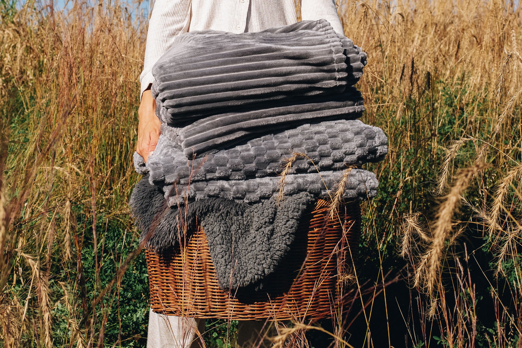 Woman Holding Basket of blankets in a wheat field