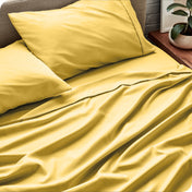 Sheet set on a bed with pillows and a plant in the background