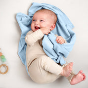 A baby lying on a receiving blanket. She has her thumb in her mouth.