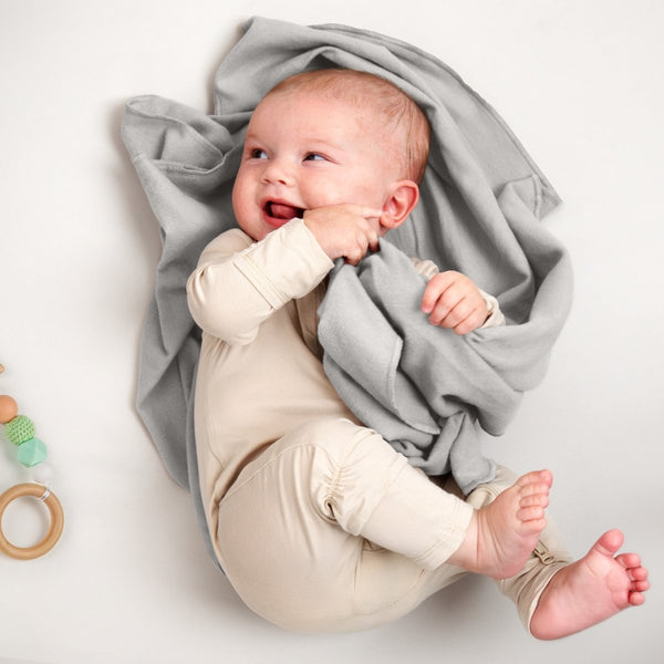 A baby lying on a receiving blanket. She has her thumb in her mouth.