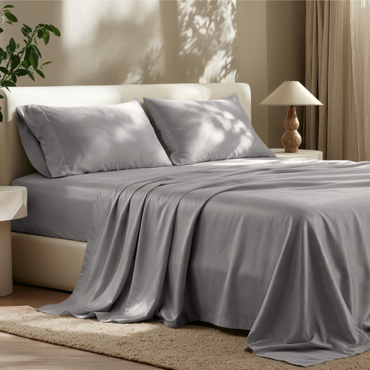 Sheet set on a bed in a bedroom with a lamp and plant.