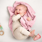 A baby lying on a receiving blanket. She has her thumb in her mouth.