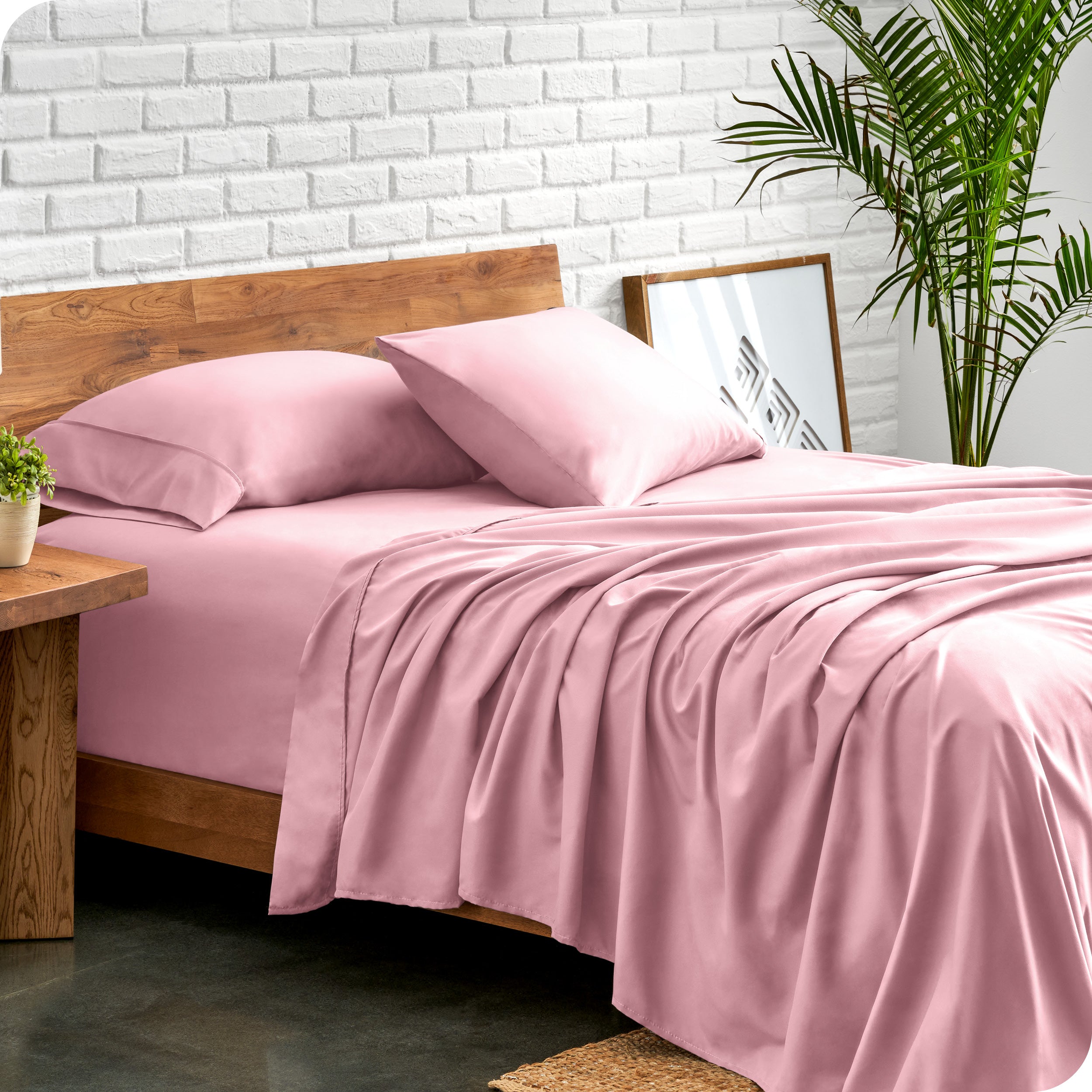 Bed with microfiber sheets against a white brick wall
