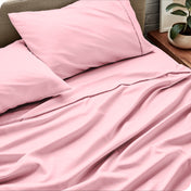 Sheet set on a bed with pillows and a plant in the background