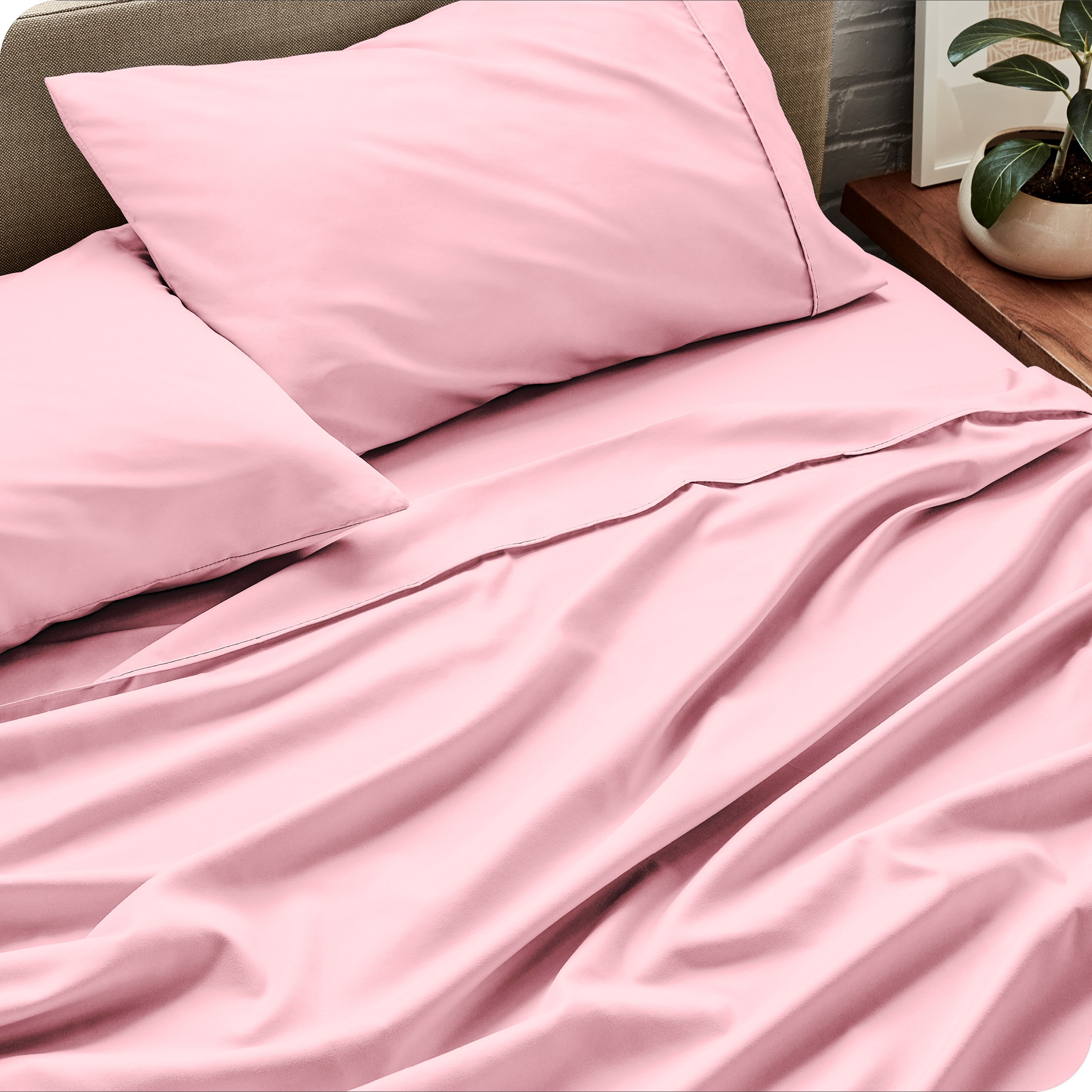 Sheet set on a bed with pillows and a plant in the background