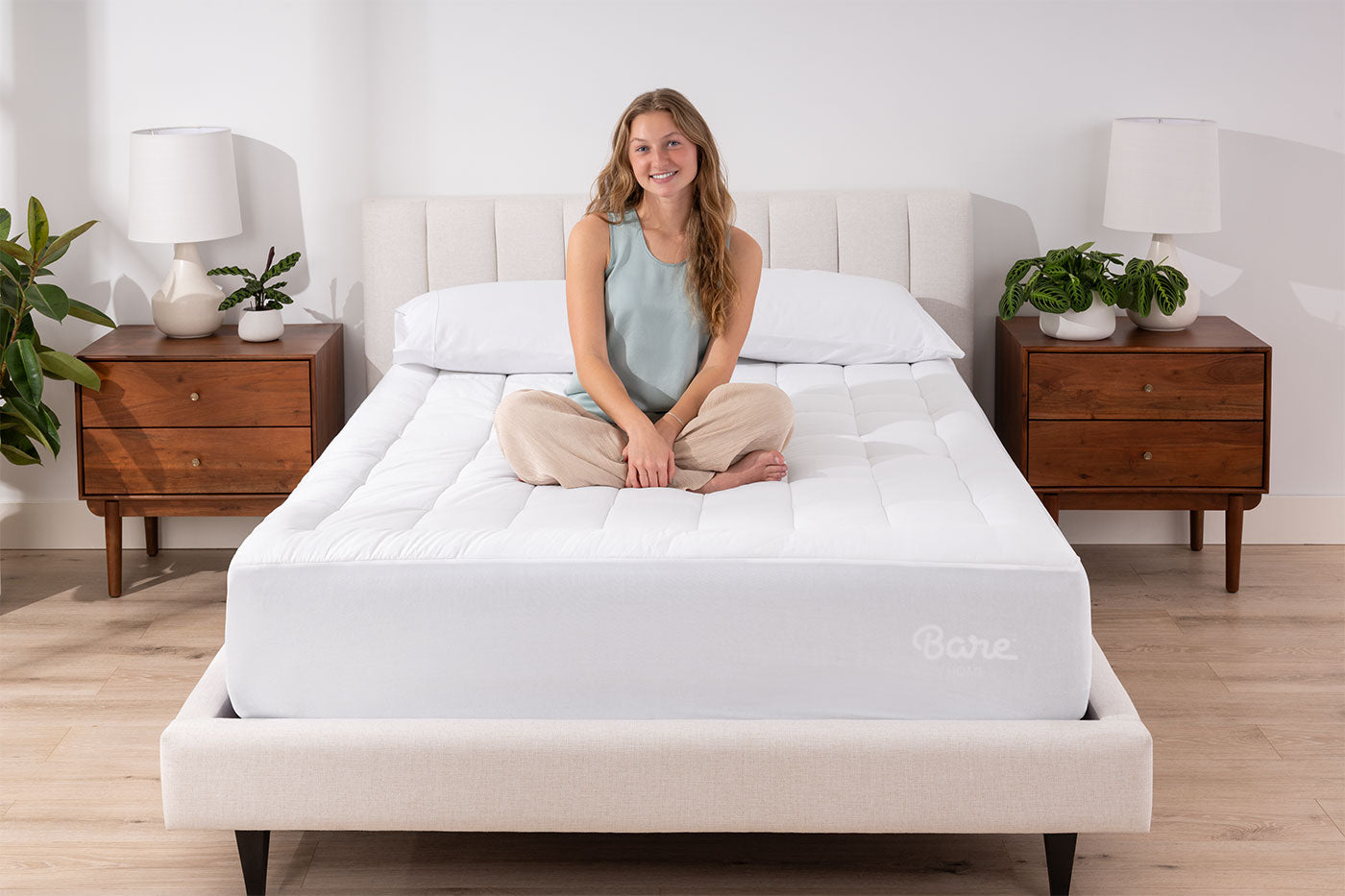 Young woman sitting on a bed  with a cotton top mattress pad