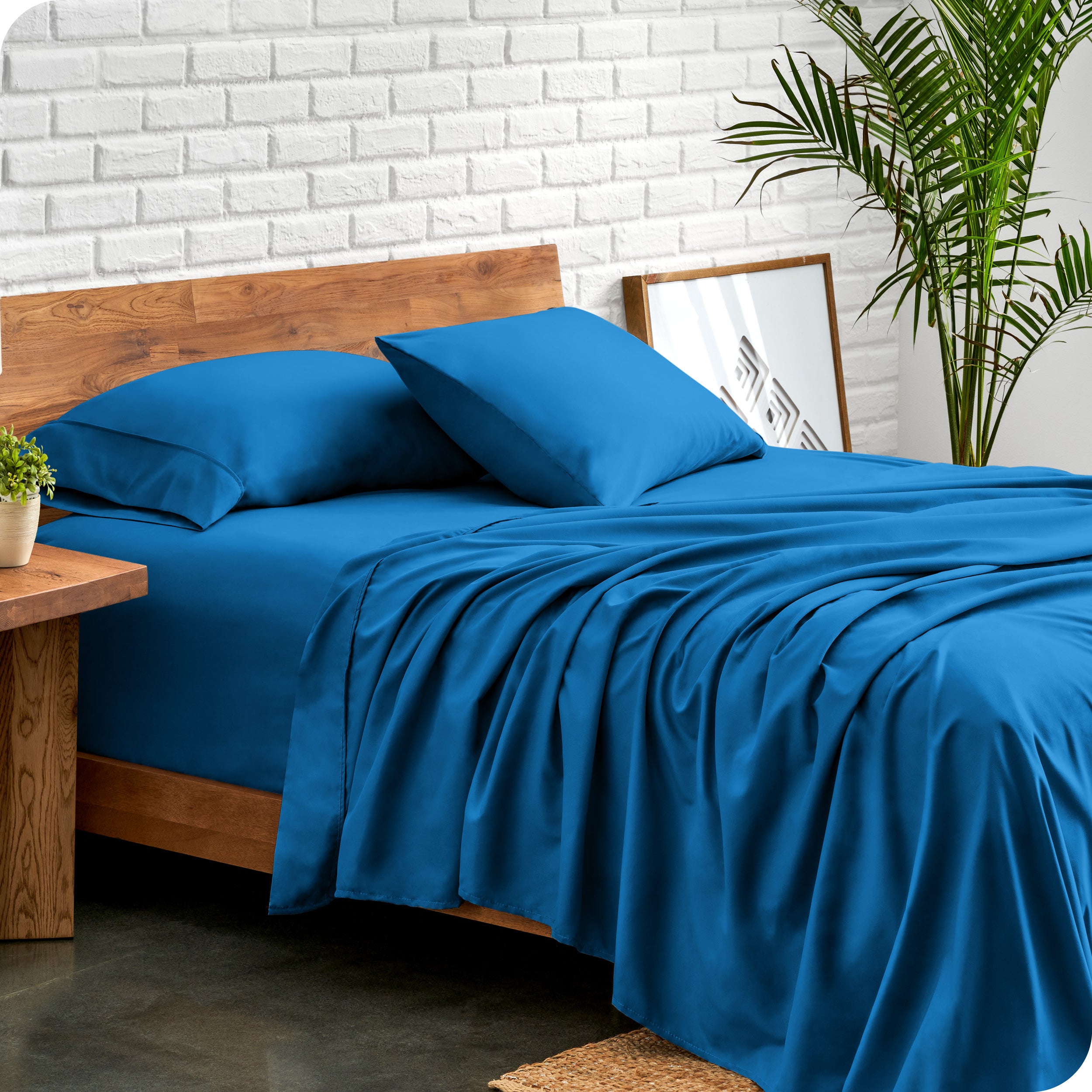 Bed with microfiber sheets against a white brick wall