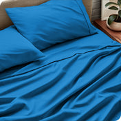 Sheet set on a bed with pillows and a plant in the background