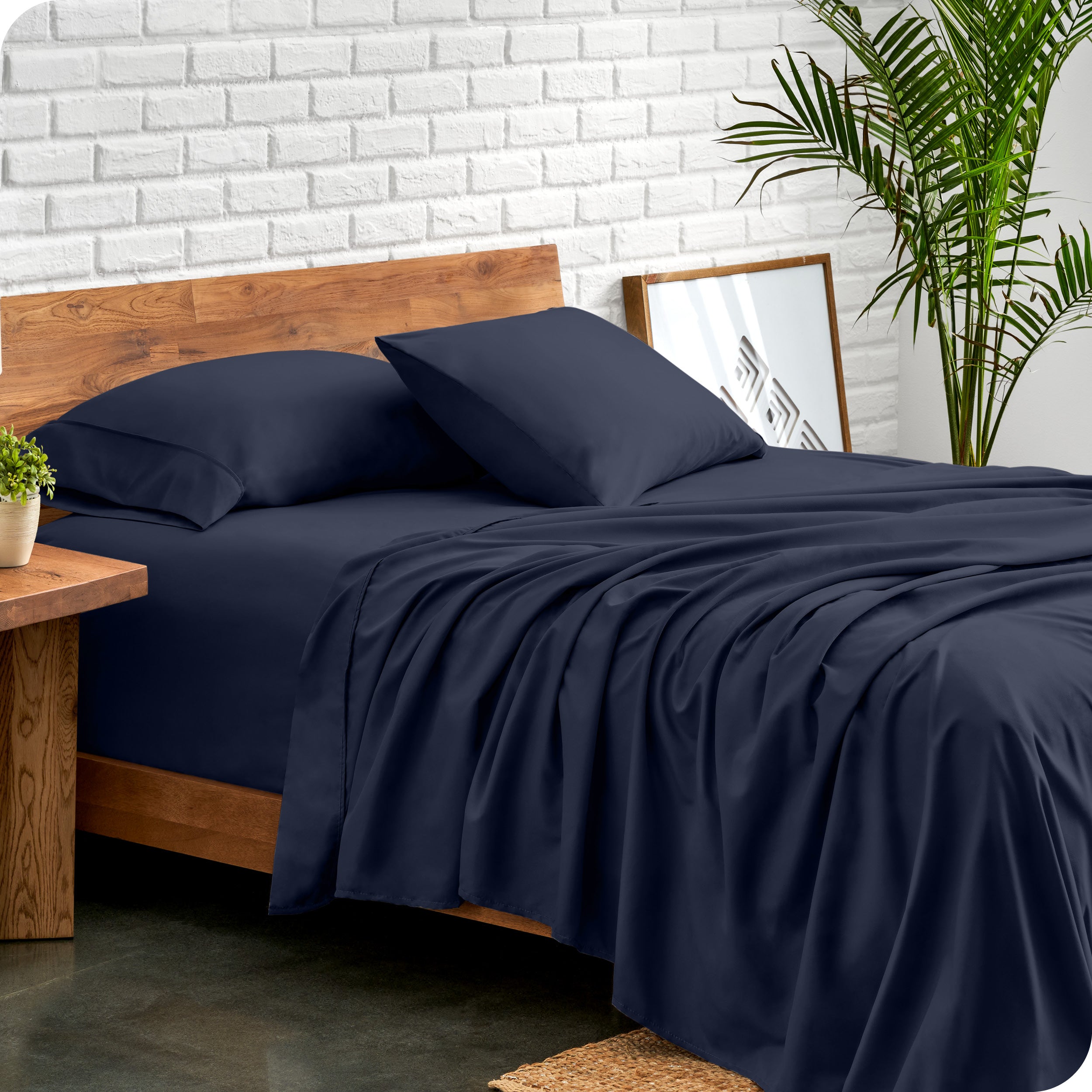 Bed with microfiber sheets against a white brick wall