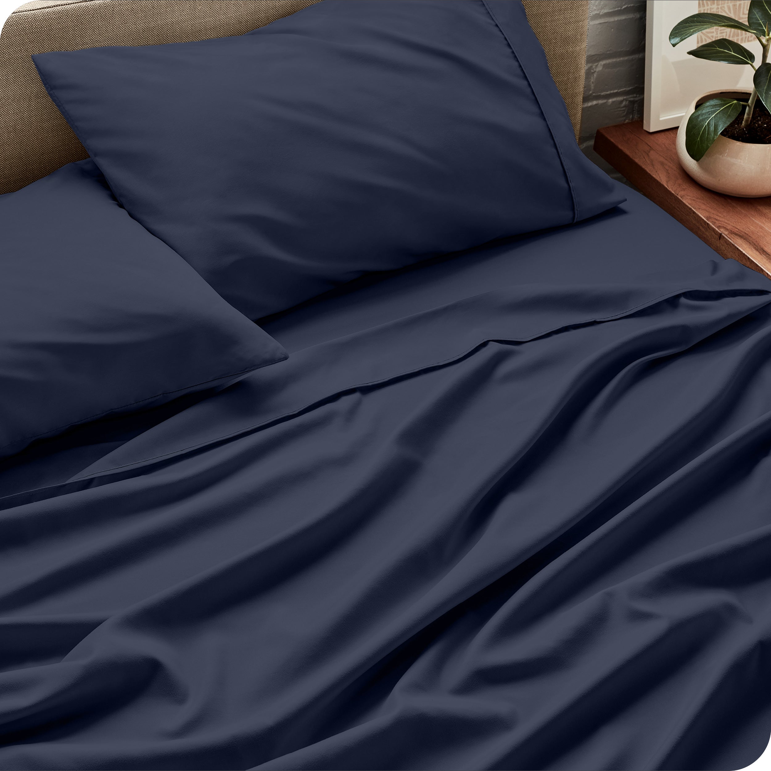 Sheet set on a bed with pillows and a plant in the background