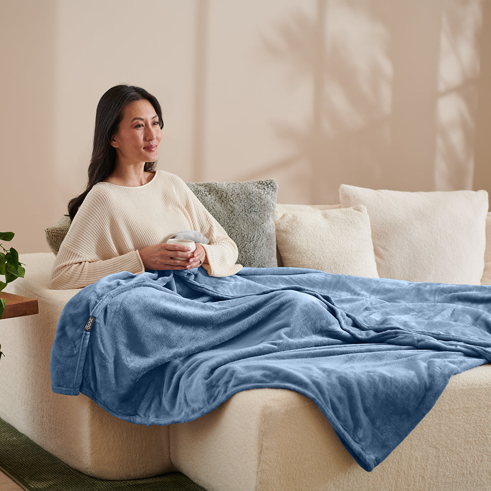 Mom Wrapped in a light blue blanket drinking tea on a couch