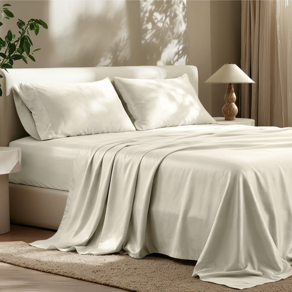 Sheet set on a bed in a bedroom with a lamp and plant.
