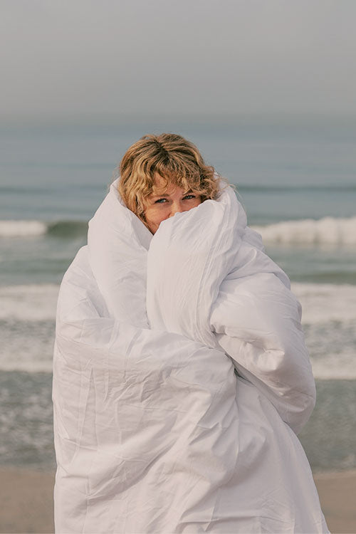 Woman wrapped in comforter at the ocean