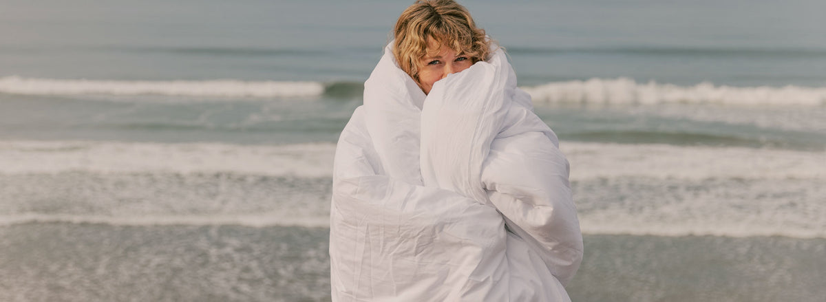 Woman wrapped in comforter at the ocean