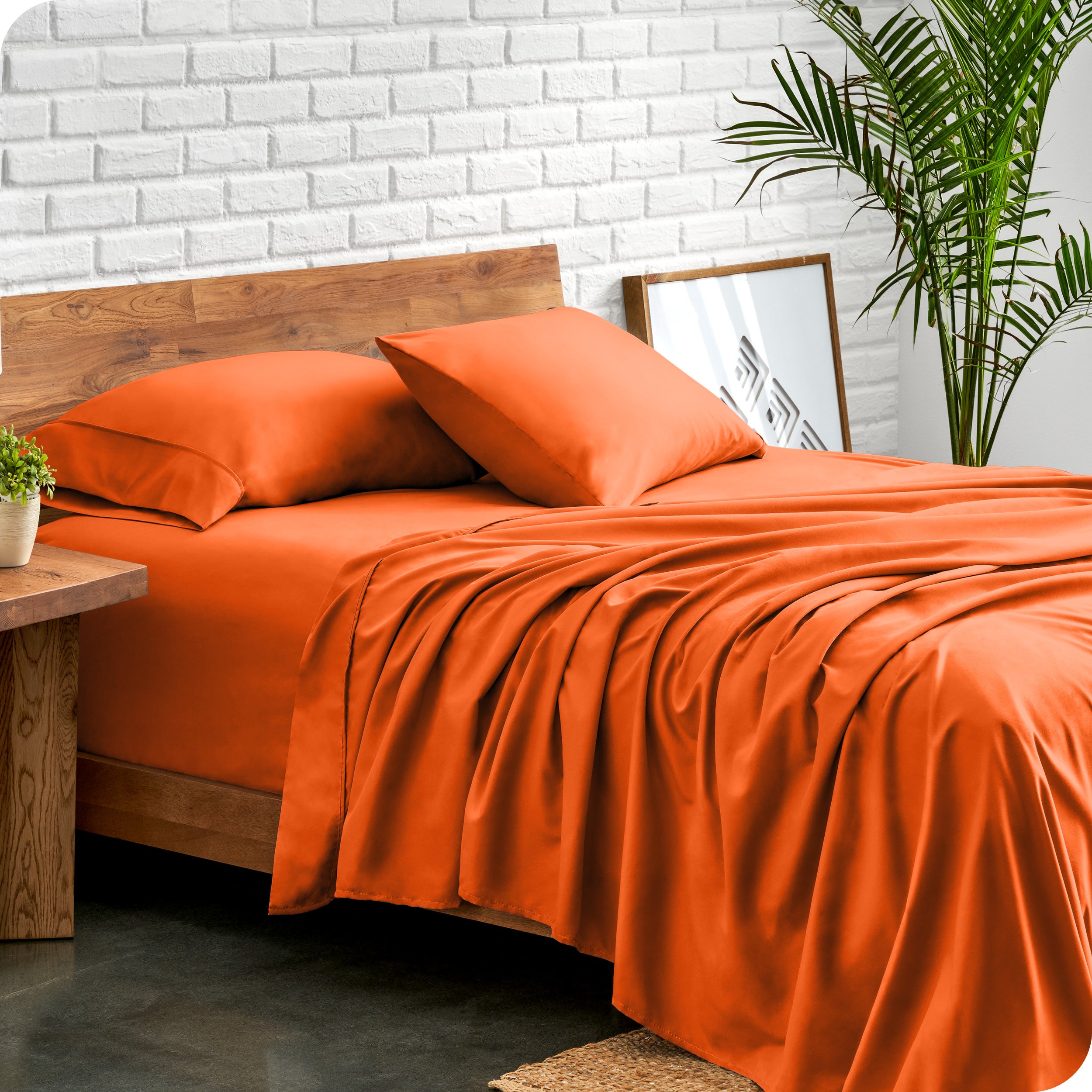 Bed with microfiber sheets against a white brick wall