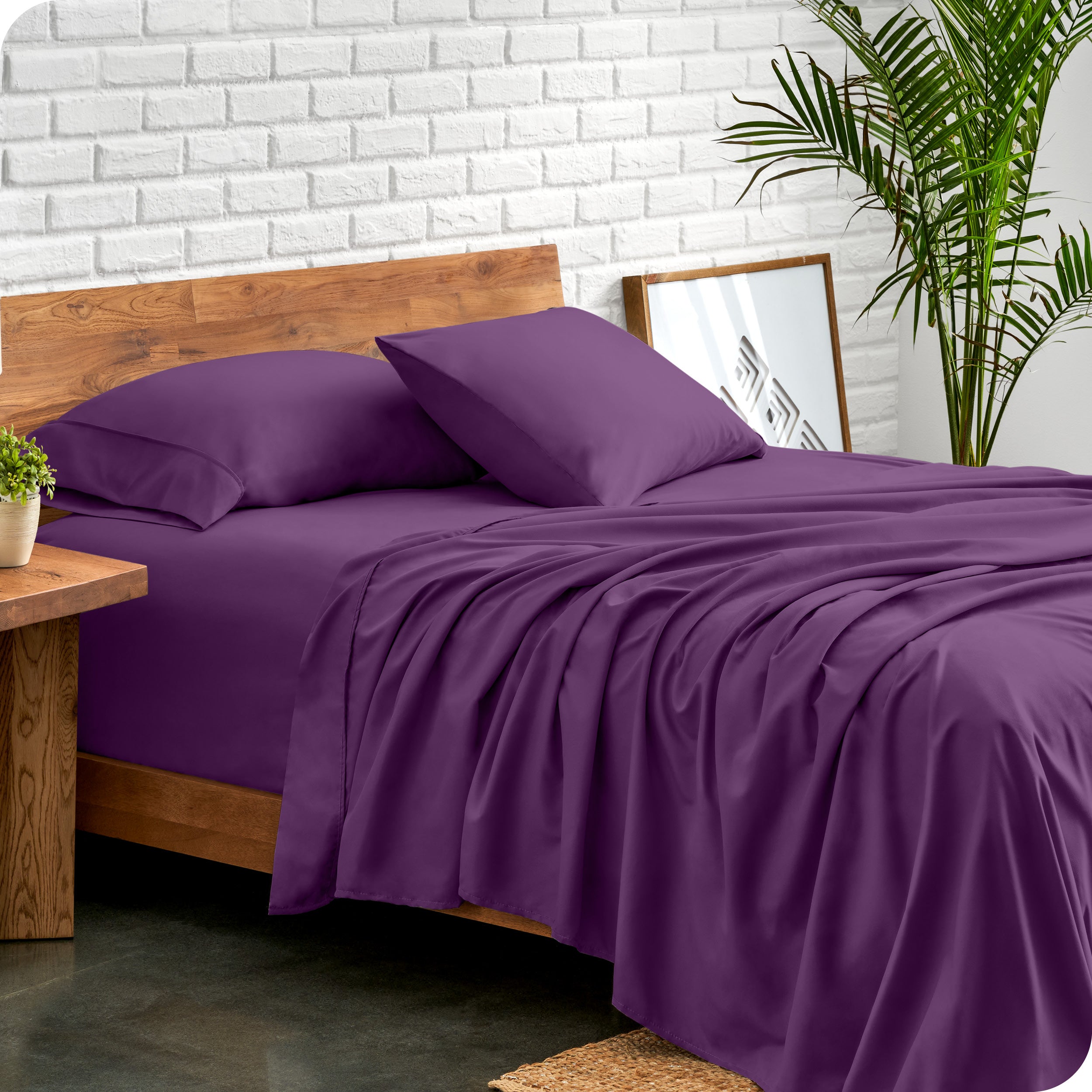 Bed with microfiber sheets against a white brick wall