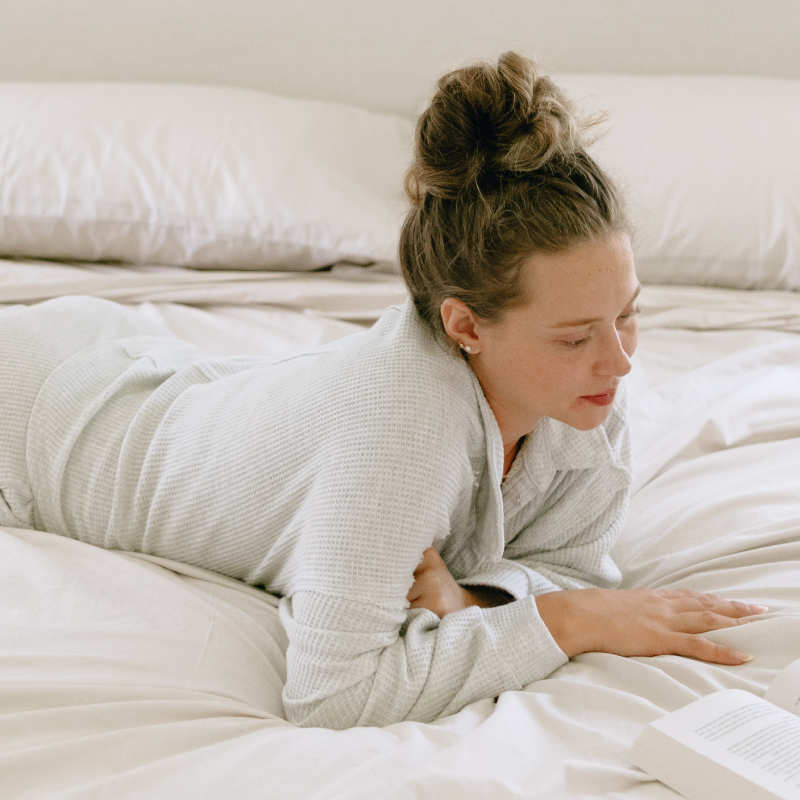 Woman lying on a bed on her stomach in cream loungewear