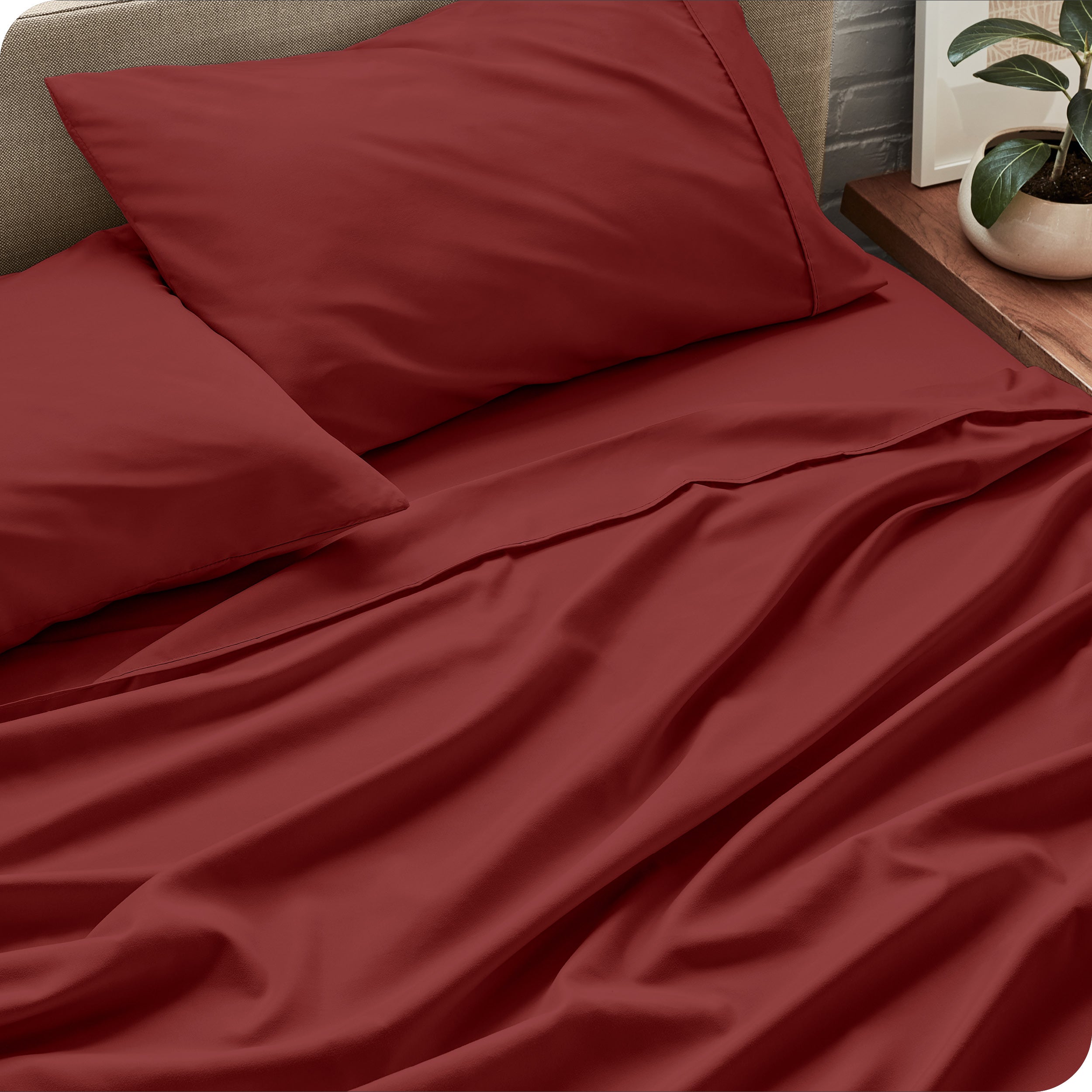 Sheet set on a bed with pillows and a plant in the background