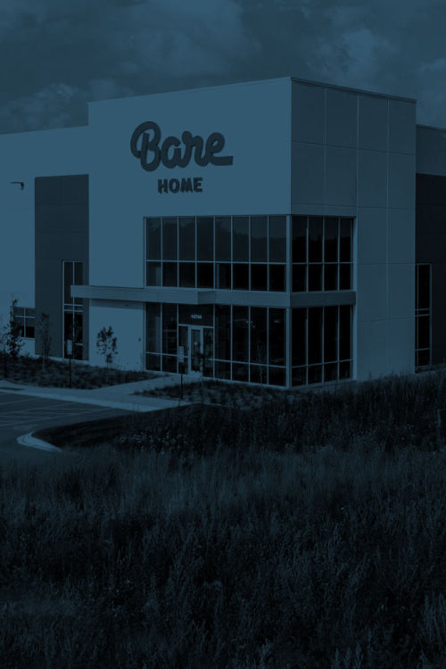 A modern building facade with large glass windows and a prominent 'Bare Home' sign on the front, shown in a dark blue-toned outdoor scene.